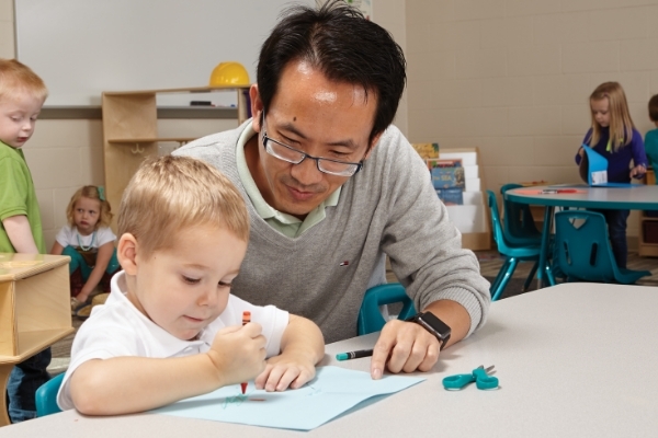 Teacher helping kindergartner 