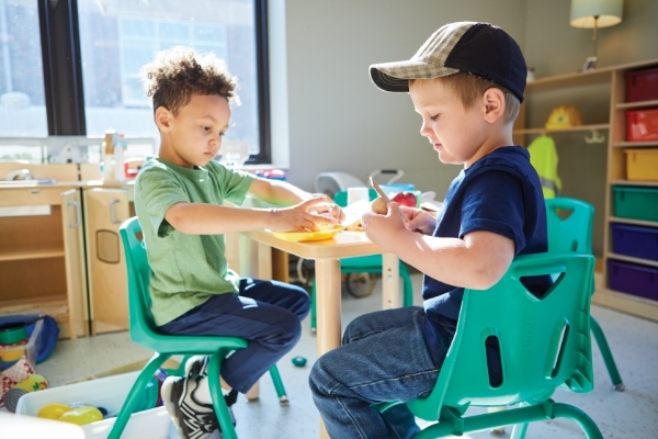 2 young boys sitting at table playing