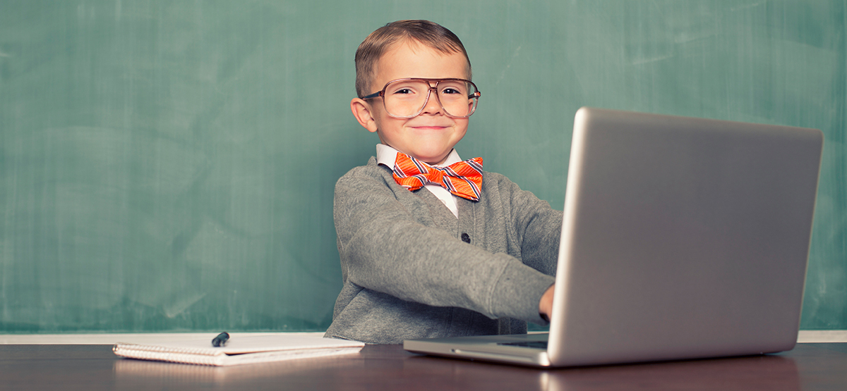 young boy with a bowtie and glasses typing on laptop