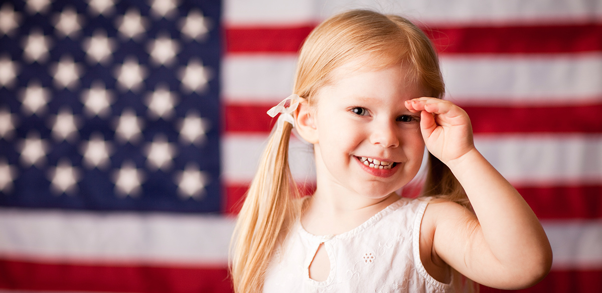 Little girl saluting with American flag in background